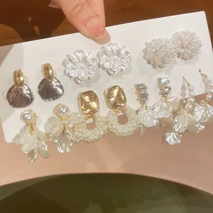 Makroaufnahme von Vintage-Perlenblumen-Ohrringen und geometrischen Kristallsteckern