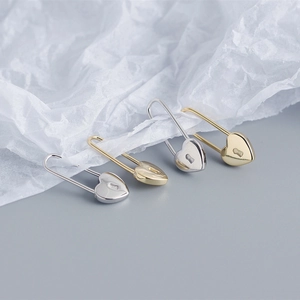 Detail of S925 sterling silver heart safety pin earrings in gold and silver finishes