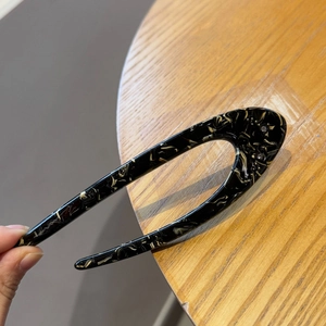 Close-up of U-shaped acetate hair pin with black yellow marble pattern and rhinestones