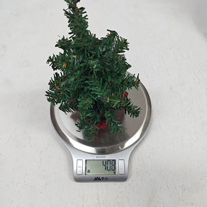 Detailed view of a 20cm mini green Christmas tree weighing 40.8g on a scale