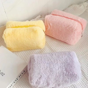 Three macaron-colored plush cosmetic bags in yellow, pink, and purple with soft faux fur
