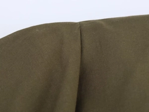 Détail d'une robe midi plissée vert olive montrant le tissu lisse et les coutures de qualité