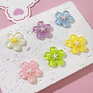 Macro shot of colorful resin cherry blossom charms with glitter on white stone surface