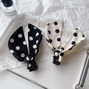 Polka dot fabric bow hair claws in black and cream beige shown on a glass tray