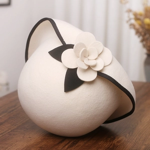 Detail of wool felt cloche hat featuring a white camellia flower and contrast trim