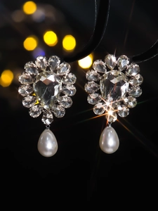 Macro shot of silver drop earrings with faceted crystals and teardrop pearls on black