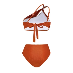 Flat lay of burnt orange textured one-shoulder bikini set with beads and high waist