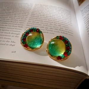 Détail de boucles d'oreilles rondes vintage avec verre dégradé sur un livre ancien
