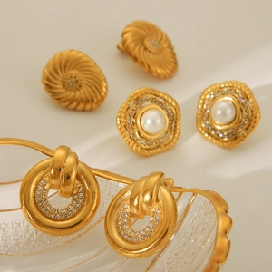 Three 18K gold-plated stainless steel earrings with pearls and crystals on white surface