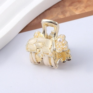 Detailed macro view of a golden poodle hair claw clip with pearls and translucent stones