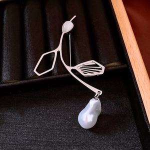 Close-up of silver plant branch brooch featuring an irregular pearl on black velvet