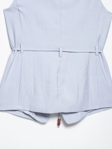 Detail of light blue cotton linen vest with belt loops and decorative wooden beads