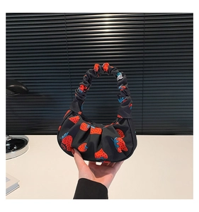 Dettaglio borsa a spalla nera con stampa a fragole e manico con design arricciato