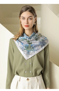 Floral silk scarf tied in a triangle knot around neck featuring blue and olive patterns