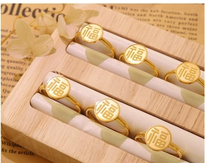 Close-up of golden Fu character ring with matte metal texture on a wooden jewelry box