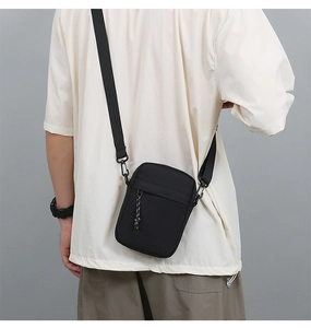 Rear view of man wearing black nylon crossbody bag with adjustable strap and zip pocket