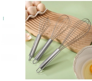 Three sizes of stainless steel whisks with round handles on a wooden tray