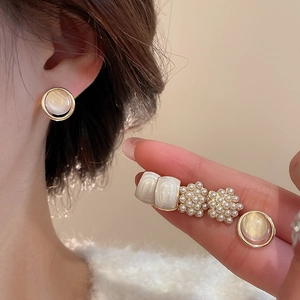 Close-up of elegant gold pearl earrings and opal studs worn for a classy daily look