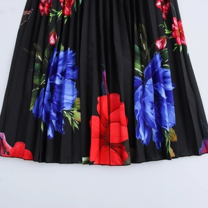 Robe longue plissée à fleurs rouges et bleues éclatantes sur tissu noir élégant