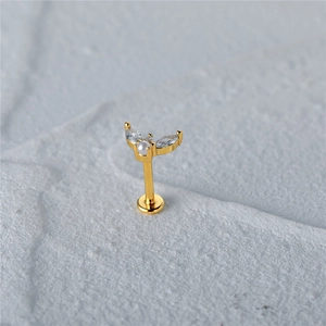 Macro view of gold piercing stud with white pearl and marquise-cut zircon stones