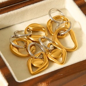 Detailed view of gold and silver irregular geometric earrings on a beige velvet tray