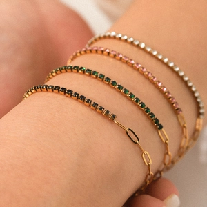 Detail of four gold-plated chain bracelets with black, green, pink, and white zircon stones