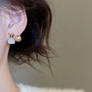 Dettaglio orecchino a farfalla in oro 18K con zircone e una perla dorata lucida