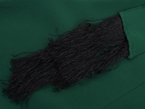 Dettaglio di nappe nere cucite su un abito lungo da vacanza verde scuro di alta qualità
