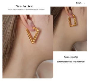 Detail of gold beaded U-shaped earrings in triangular and rectangular geometric designs