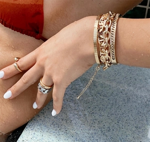 Close-up of luxury gold-plated stackable rings and bracelets with water droplets on skin