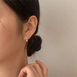 Detail of silver bowknot earrings with water drop zircon pendant worn by model