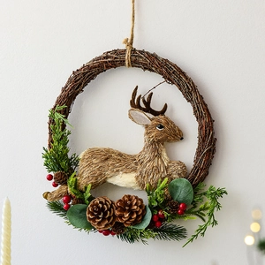 Couronne de Noël avec renne, pommes de pin et baies sur un cercle en rotin naturel