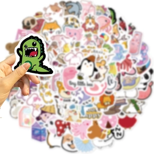 Close-up of a hand holding a cute green dinosaur sticker from a 100-piece cartoon set