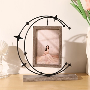 Moon-shaped metal photo frame with hanging wooden border on a stable solid wood base