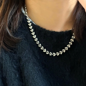 Detail view of silver wheat ear chain necklace worn on a black minimalist sweater