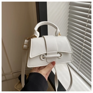 Close-up of white lychee leather texture and gold hardware on a stylish handbag