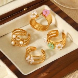 Detailed view of four golden flower pearl rings arranged in a luxury wooden jewelry box