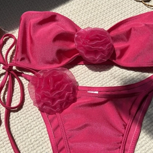 Pink bikini set featuring 3D rose flower accents and shiny metallic finish fabric