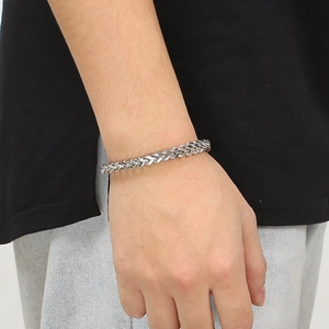 Polished silver stainless steel braided chain bracelet worn by a model on wrist