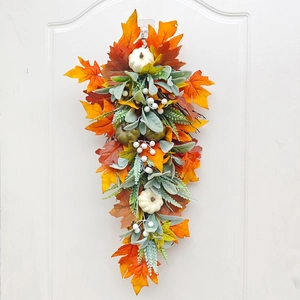 Detailed view of autumn teardrop wreath with white pumpkins and maple leaves on a white door
