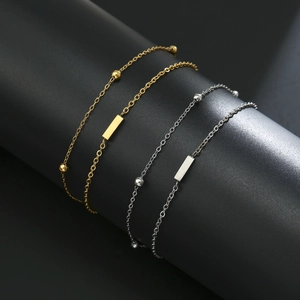 Detail of silver and gold stainless steel beaded bracelets with polished rectangular charms