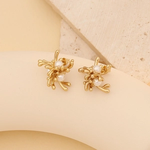 Macro detail of golden shell shaped pearl earrings on textured natural stone background