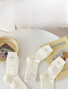 Flat lay of white diamond-patterned knit socks with breathable mesh and bow details