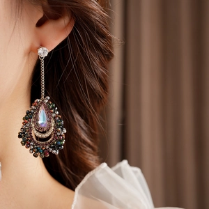 Detail of silver drop tassel earrings with teardrop crystal on a female model