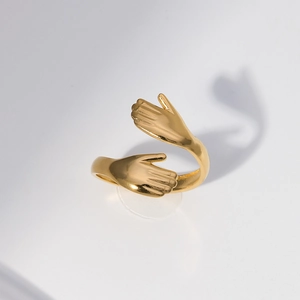 Detail shot of a golden stainless steel embrace ring with a unique hand hug design