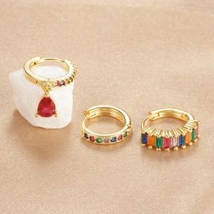 Detail of luxury gold plated earring set with colorful gemstones on silk fabric background