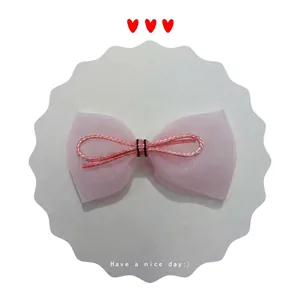 Pink tulle bow hair accessory with woven center knot on a white decorative card display