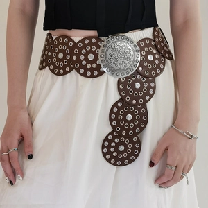 Detail of western vintage belt with large floral engraved silver buckle and leather discs
