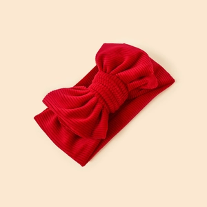 Detailed view of red corduroy bow headband for babies with soft textured fabric