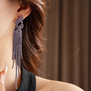 Gros plan d'un mannequin portant des boucles d'oreilles à franges de strass violets